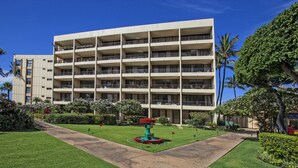 A multi-story hotel with a central courtyard, surrounded by lush greenery and palm trees. - Sugar Beach Resort - Maui Condo & Home (Kihei)