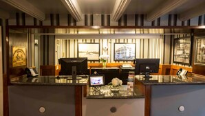 A hotel reception area with a desk, computer, phone, and framed pictures on the wall. - Delta King Hotel (Sacramento)