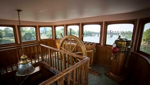 A room with a wooden railing, a captain's wheel, and a brass lamp. - Delta King Hotel (Sacramento)
