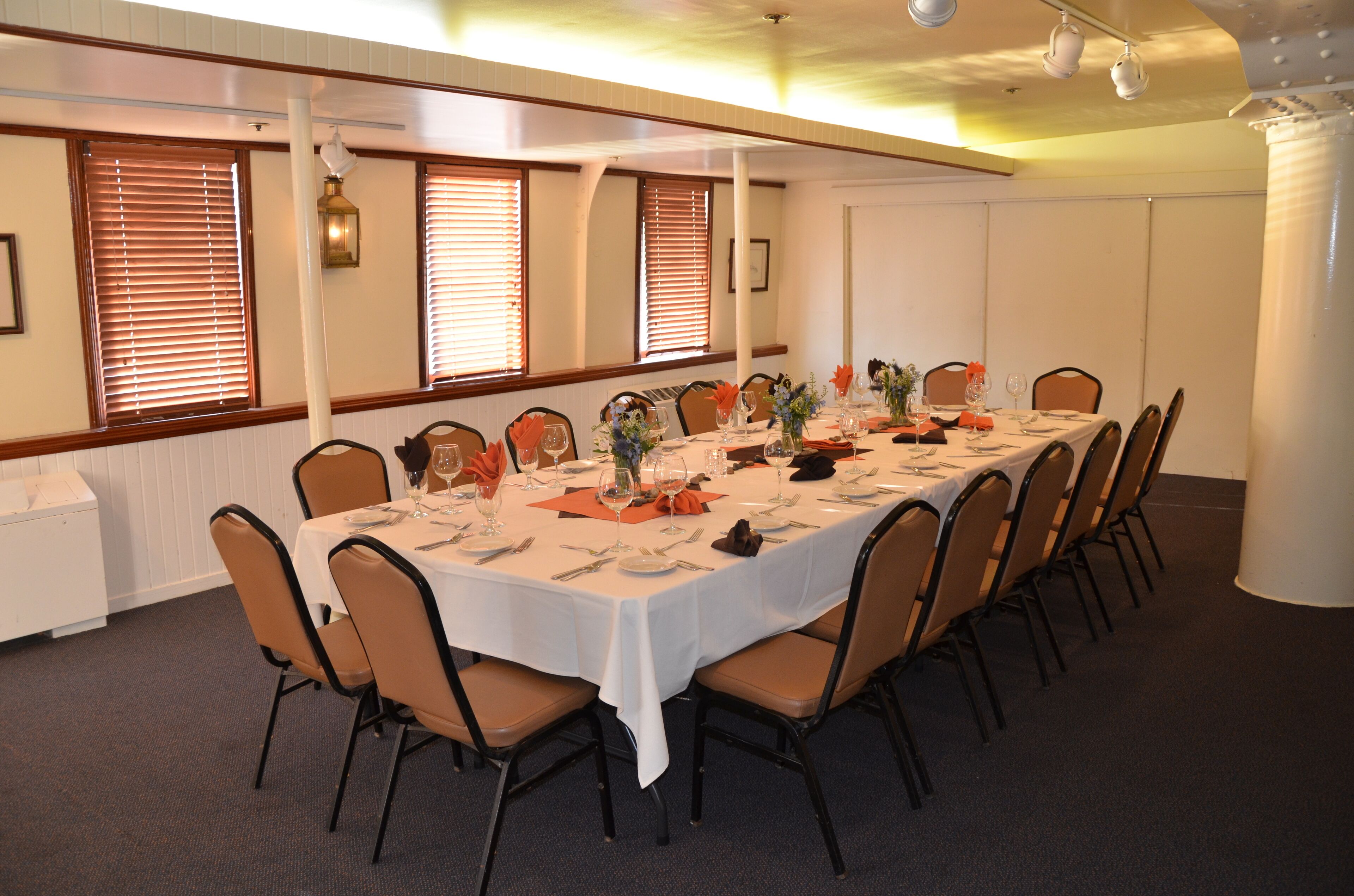 A conference room with a long table set for a meeting, surrounded by chairs.