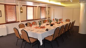 A conference room with a long table set for a meeting, surrounded by chairs.