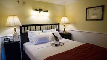 Habitación de hotel con cama, dos lámparas de noche, un reloj y un cuadro en la pared.