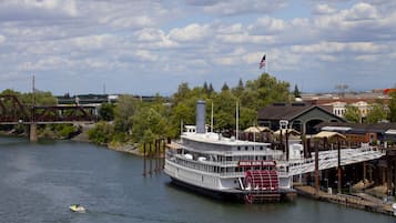 A large riverboat hotel docked at a pier with a bridge in the background.