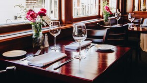 A dining area with wooden tables, chairs, and a vase with flowers. - Delta King Hotel (Sacramento)