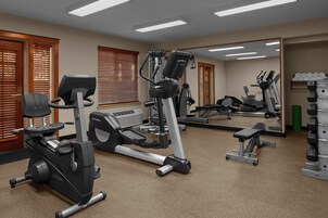 A gym with cardio machines, weight equipment, and a large mirror.