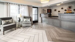 Una habitación de hotel moderna con sofá, sillón y una mesita con lámpara.