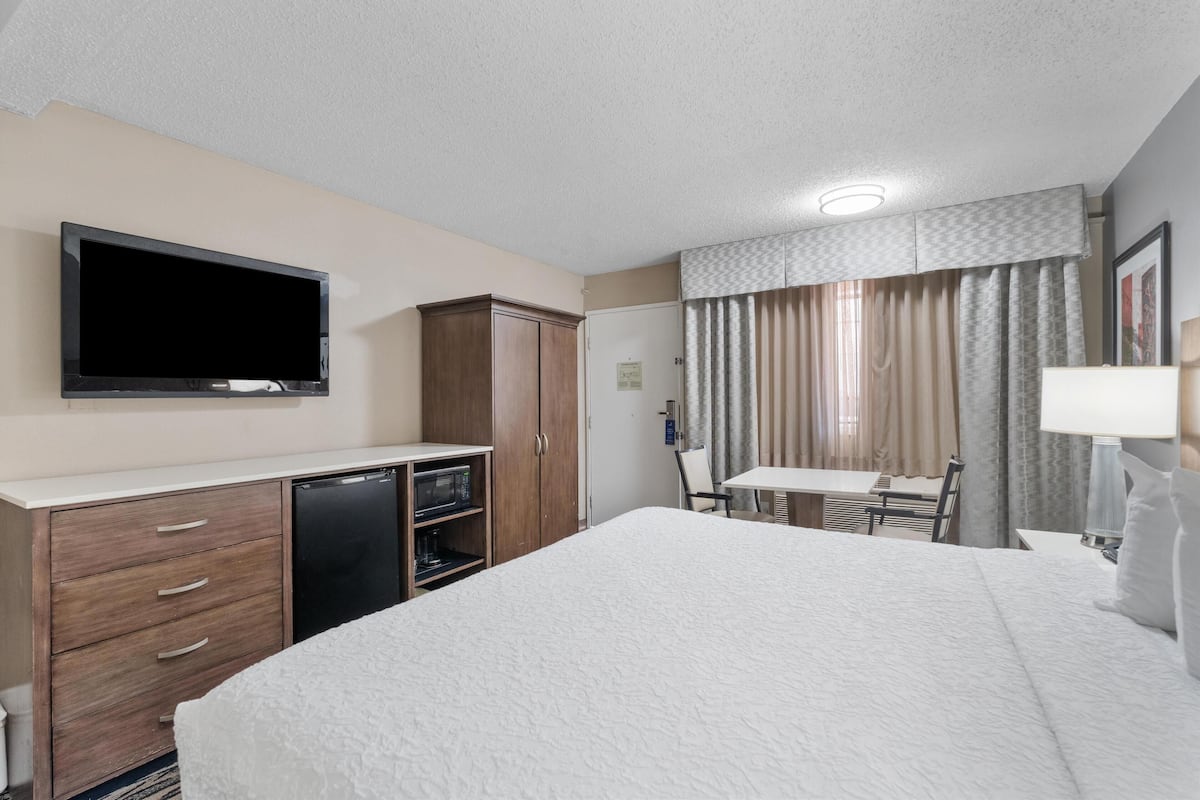 A hotel room with a bed, a television, a desk, and a wardrobe.