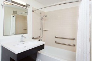 A bathroom with a white sink, a mirror, a shower with a glass door, and a bathtub.