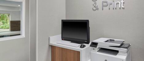 A reception desk with a computer monitor, keyboard, and HP printer.