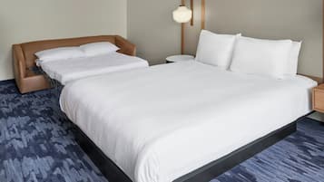 A large bed with white linens, a wooden headboard, a bedside table, and a wall-mounted lamp.