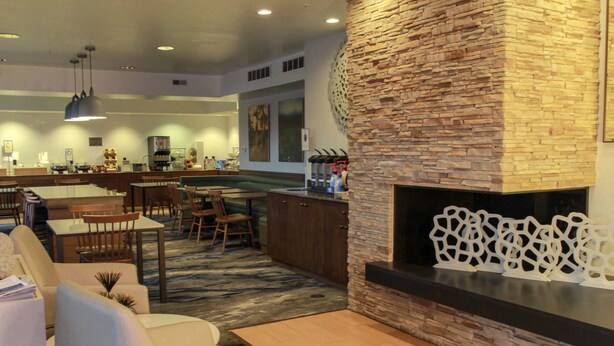 A spacious living area with a fireplace, a bar, and a seating area with sofas and chairs. - Fairfield by Marriott Kalamazoo West (Kalamazoo)