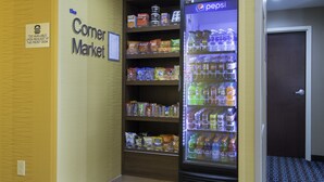 Ein Eckeladen mit einem Pepsi-Kühlschrank, Verkaufsregalen für Snacks und einem Schild mit der Aufschrift 'Corner Market'.