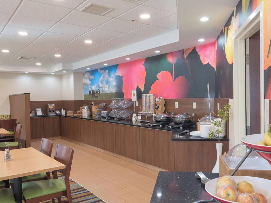 Un comedor de hotel con un mostrador de bufé, mesas dispuestas y un mural colorido en la pared.