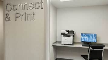 A workspace with a printer, a computer monitor, and a chair.