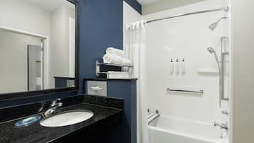 Un baño moderno con un lavamanos de encimera negra, una bañera blanca y una ducha con puerta de vidrio.