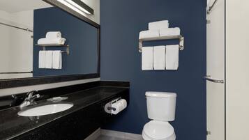 Un baño moderno con encimera negra, lavamanos blanco y un inodoro.