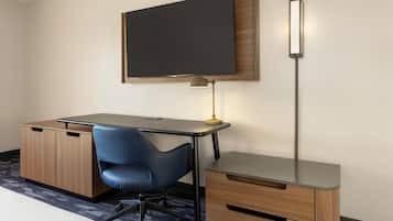 Ein Hotelzimmer mit Schreibtisch, Stuhl, Fernseher und Lampe.