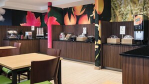 Un restaurante con paneles de madera, una barra con una máquina de café y una pared decorada con murales de frutas y trigo.