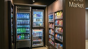Un mercado de barrio con dispensadores refrigerados de bebidas y estantes con productos de snack.