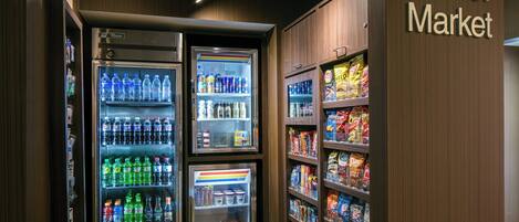 A corner market with refrigerated beverage dispensers and snack shelves.