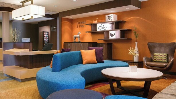 Un vestíbulo moderno con un sofá azul, un sillón de cuero marrón y un mostrador de recepción.