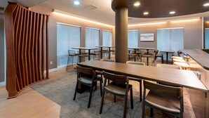 A modern conference room with a long table, multiple chairs, and a wooden partition.