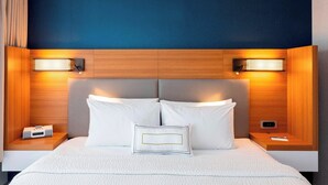 A modern hotel room with a large bed, two bedside tables, and built-in lighting.