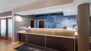 A hotel reception desk with a modern design, a clock, and a digital screen.