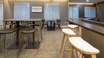 A modern hotel lobby with a bar area, seating arrangements, and a sign indicating 'SPRINGHILL SUITES MARRIOTT'.