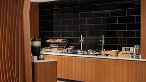 A modern kitchen with a black tiled backsplash, wooden cabinets, and various breakfast items on the counter. - Springhill Suites By Marriott Houston Brookhollow (Houston)
