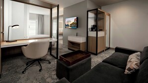 A modern hotel room with a desk, chair, sofa, and a large mirror. - Springhill Suites By Marriott Houston Brookhollow (Houston)