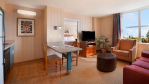 Une chambre d’hôtel comprenant un coin repas, une télévision, un canapé et une fenêtre donnant sur un paysage agréable.