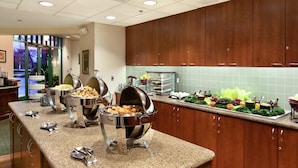 Un buffet proposant différents postes de service, notamment un poste dédié aux viandes, un bar à salades et un présentoir de fruits.