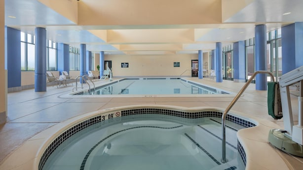 Une piscine intérieure à l’eau claire, entourée de murs bleus et beiges, et dotée d’un plafond avec des luminaires encastrés.