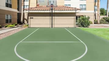 Una cancha de baloncesto exterior con superficie verde y aro.