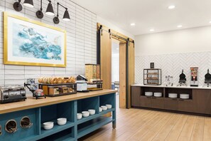 Una barra de desayuno con una máquina de café, bagels y un fabricante de gofres.