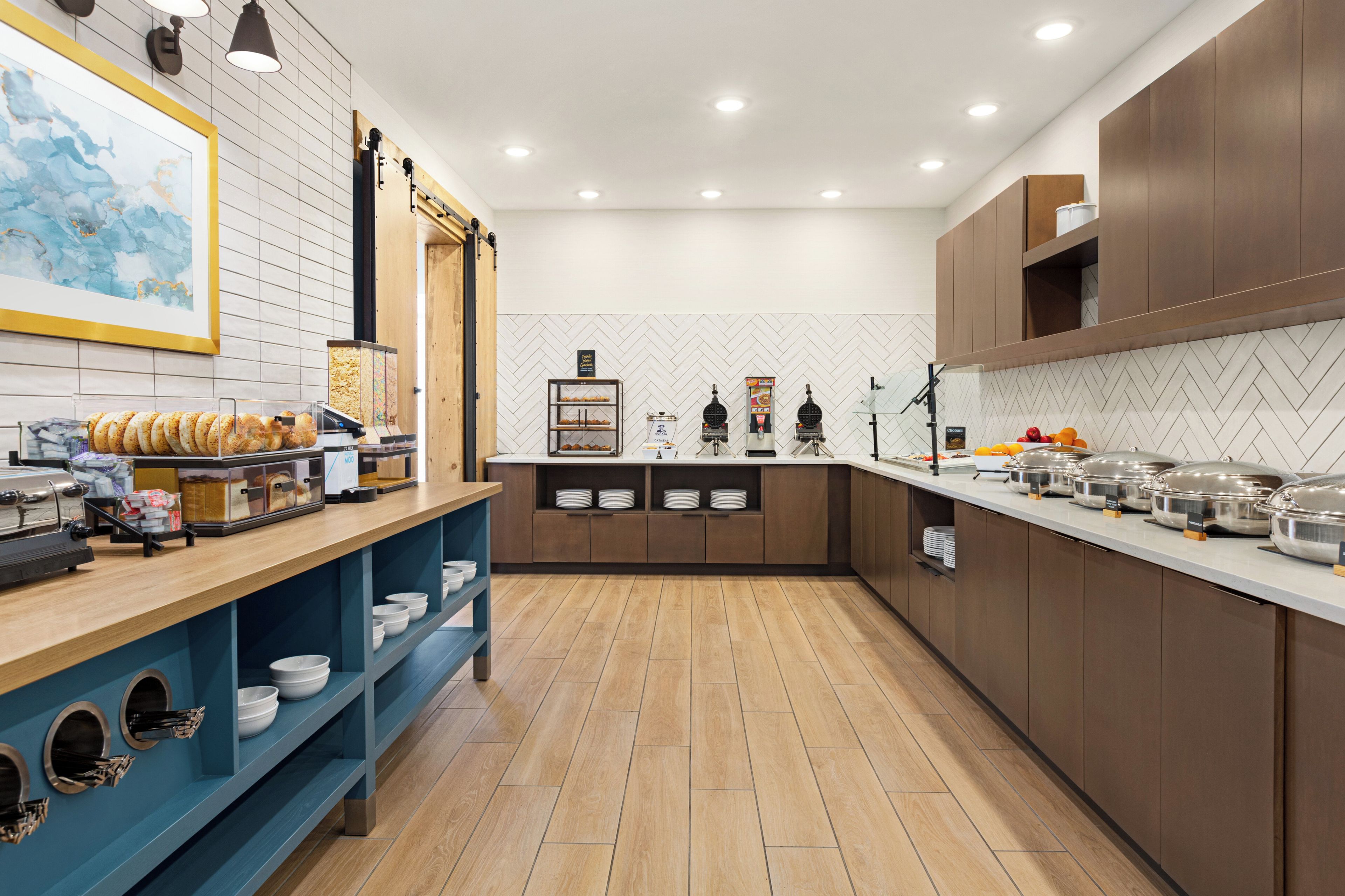 Una cocina moderna con salpicadero de baldosas tipo espiga, armarios de madera y varios dispensadores de alimentos.