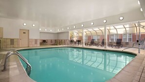 An indoor swimming pool with a metal ladder, tiled walls, and a seating area with tables and chairs. - Homewood Suites Dallas/Park Central (Dallas)