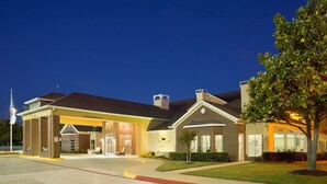 A hotel with a covered entrance, a flagpole, and a well-maintained lawn. - Homewood Suites Dallas/Park Central (Dallas)