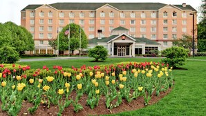 Ein Hotel mit einer symmetrischen Fassade, einem zentralen Eingang und einem gepflegten Garten mit Tulpen.