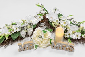 Un'elegante composizione con fiori bianchi, una candela e lettere di legno che formano la scritta 
