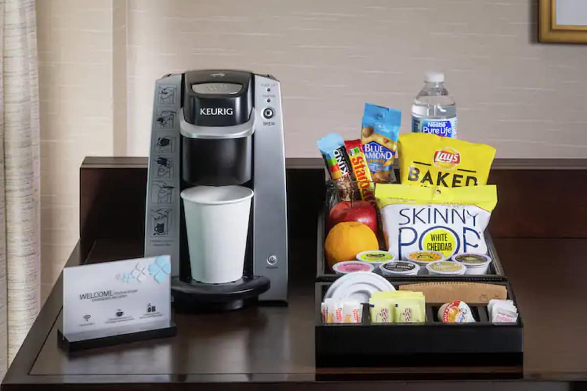 Una macchina da caffè, un cartello di benvenuto e un vassoio con snack e condimenti.
