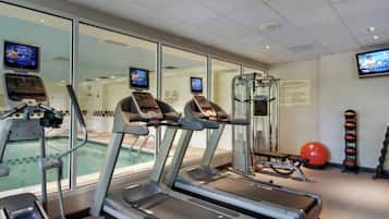 A gym with treadmills, a pool, and exercise balls.