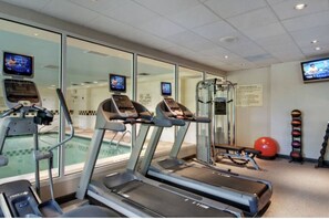Una palestra con tapis roulant, una piscina e palle da ginnastica.