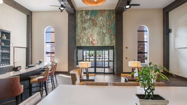 A spacious hotel lobby with a bar area, seating, and a large window with a view.