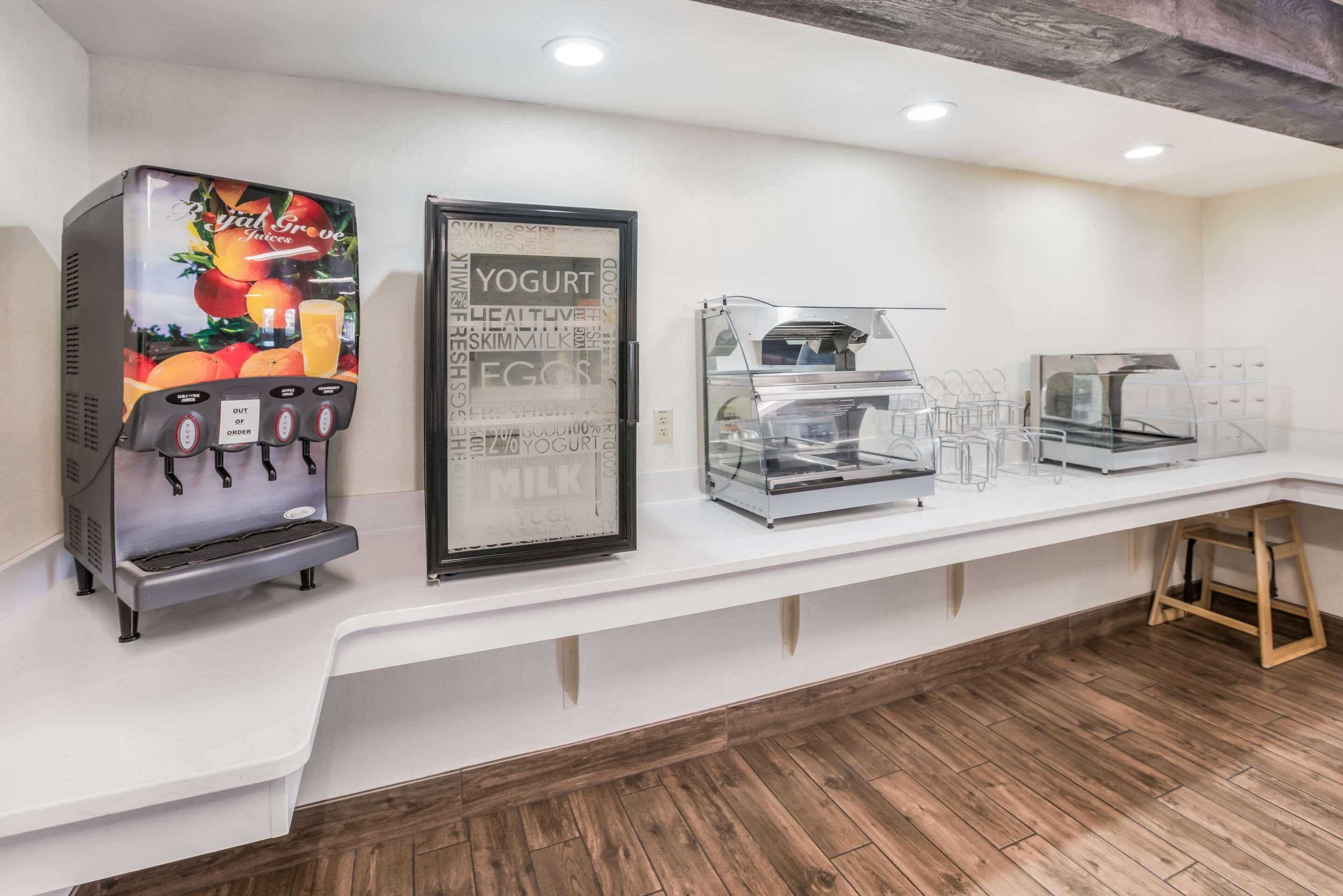 A self-serve station with a fruit juice dispenser, a refrigerated yogurt display, and a coffee machine.