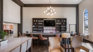 A bar area with seating, a television, and shelves with bottles.