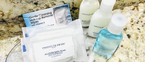 Een badkamermeubel met verschillende huidverzorgingsproducten, waaronder een pakje make-up reinigingsdoekjes, bodylotion en een fles shampoo.