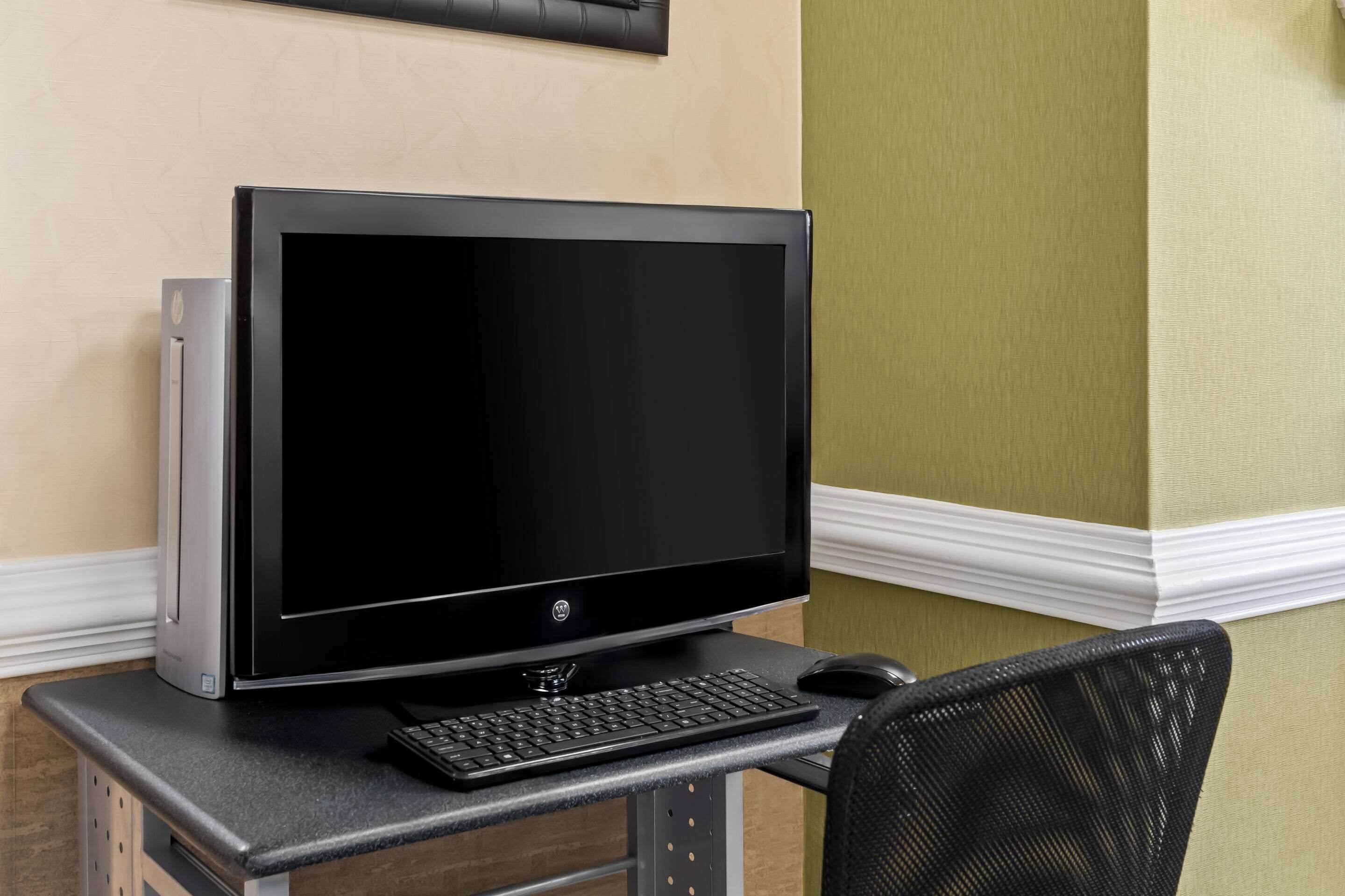 A computer desk with a monitor, keyboard, and mouse.