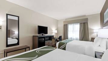 Une chambre d’hôtel avec deux lits, un bureau, une télévision et une fenêtre avec des rideaux.